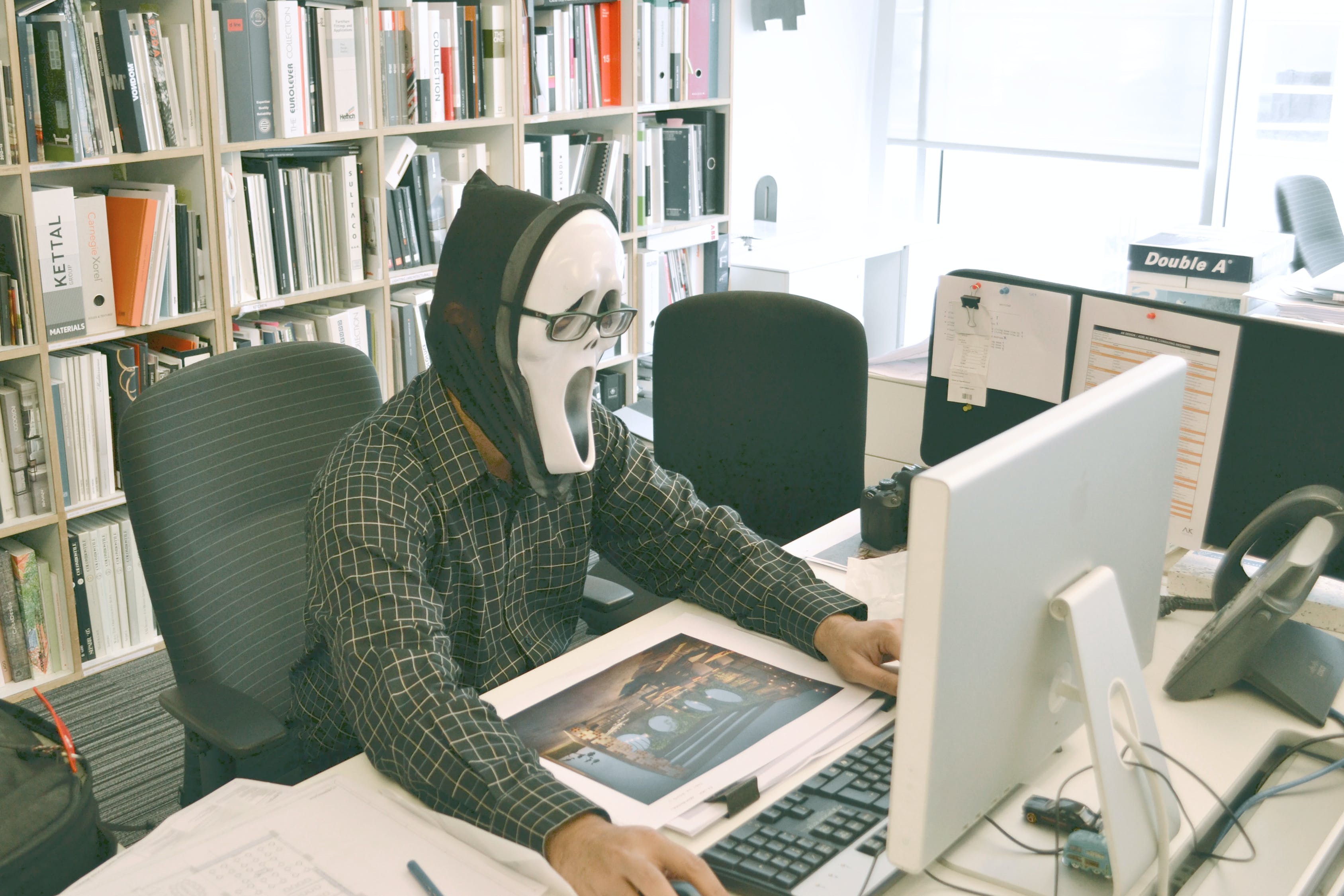 A man in a ghost mask sending a scam email