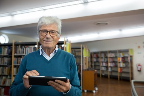 An elderly man holding a tablet