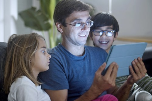 A dad and his two children looking at a tablet