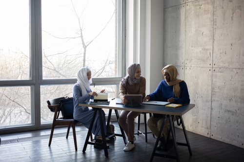 Three women talking, sat at a table