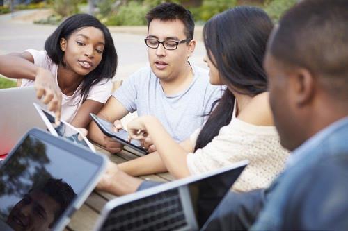 A group of young people sat looking at a tablet