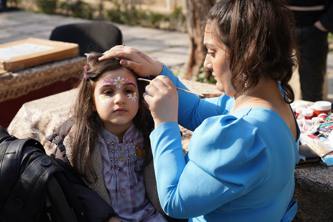 Woman painting flower design on girl's face